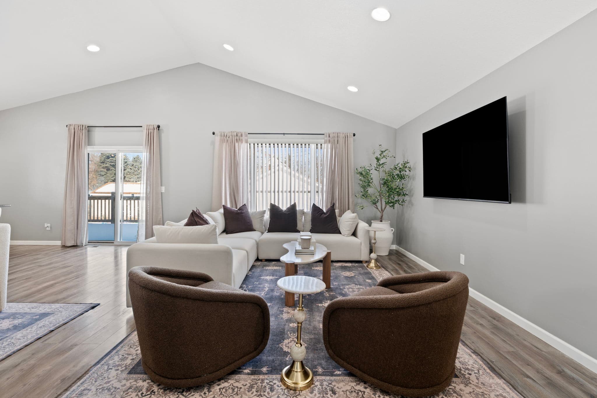 Vaulted-ceiling living room with white sectional and sliding door to the deck