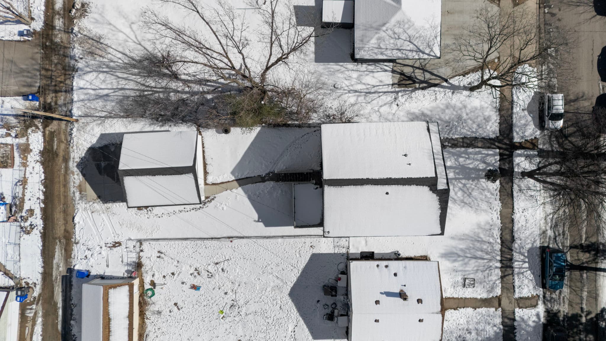 Top-down aerial of the roof, deck, walkway, backyard, and garage