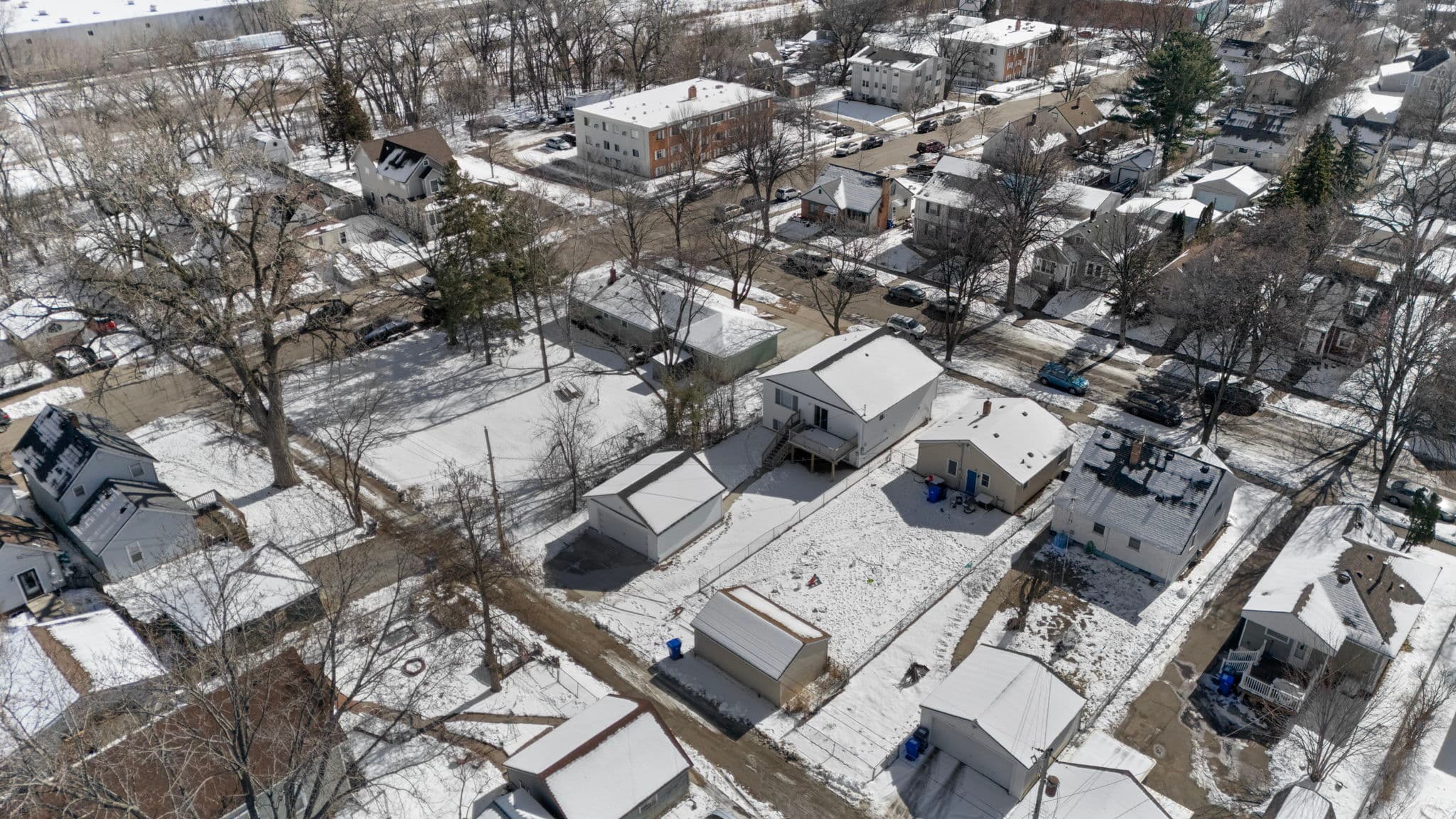 Aerial view of the home, deck, and garage among neighboring houses