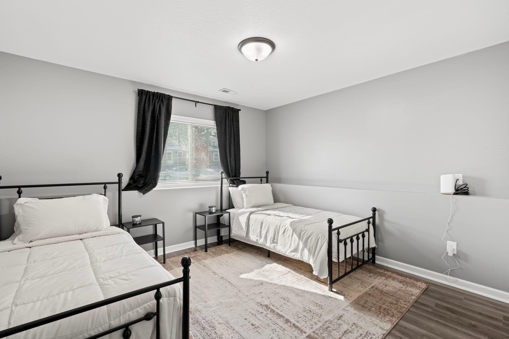 Lower-level bedroom with two twin beds, matching nightstands, and a beige rug