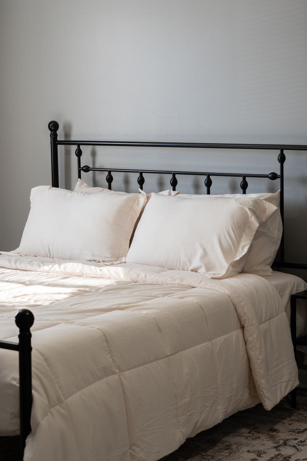 Black metal headboard with cream pillows and comforter