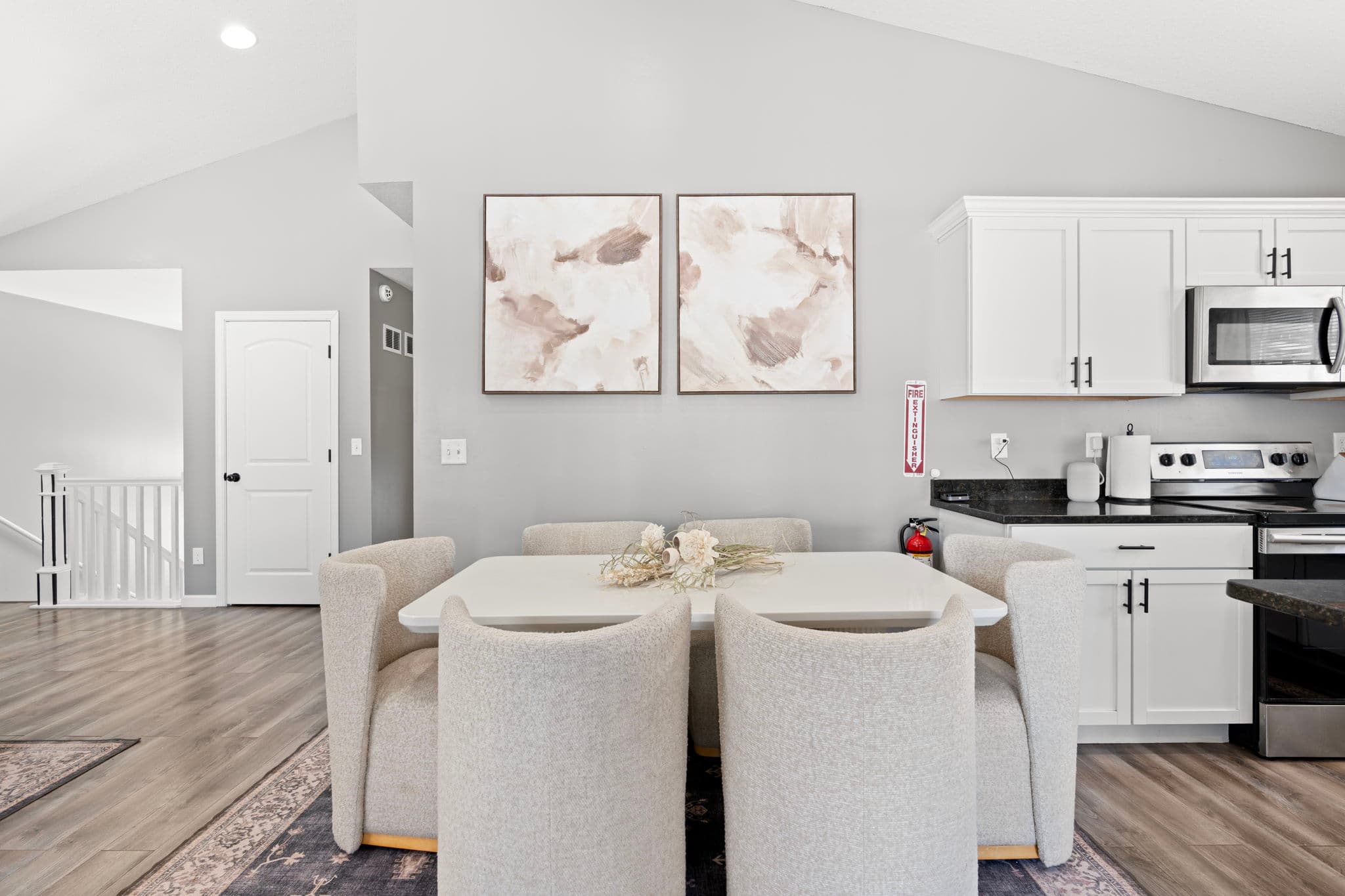 Dining table with six upholstered chairs beneath two abstract prints