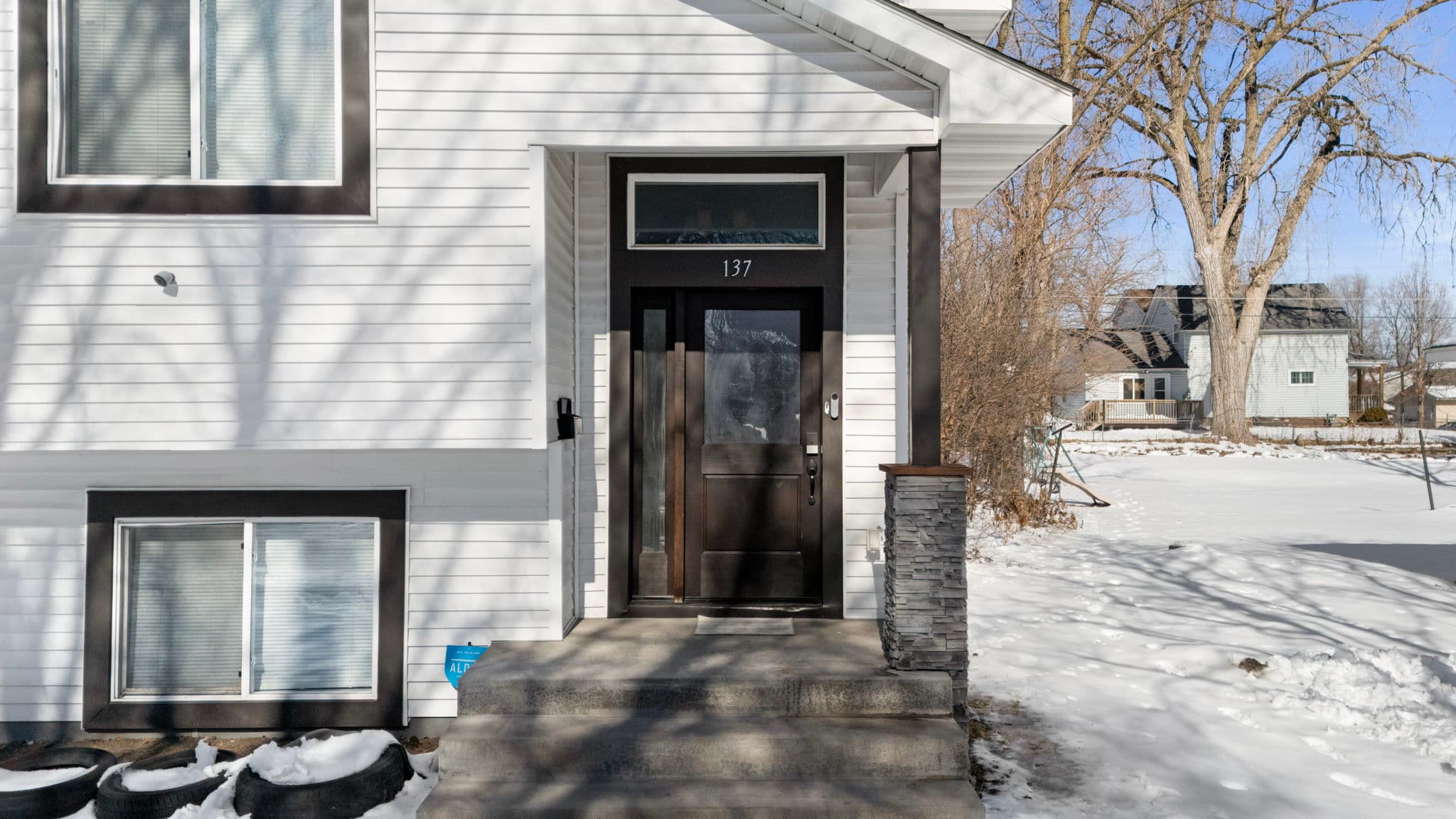 Dark wood front door with sidelight, transom window, and house number 137