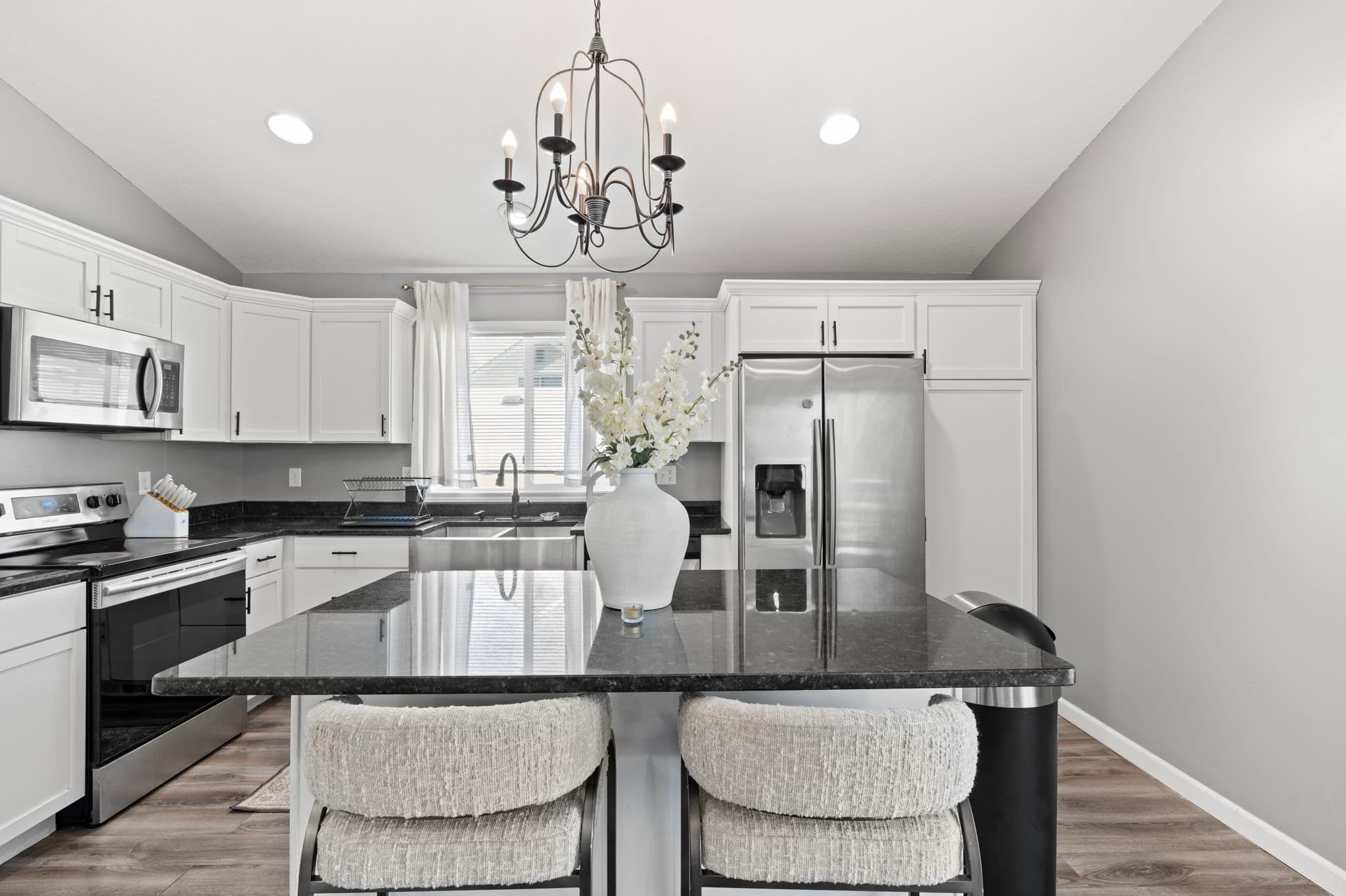 Kitchen island with granite top, flowers, and upholstered bar stools