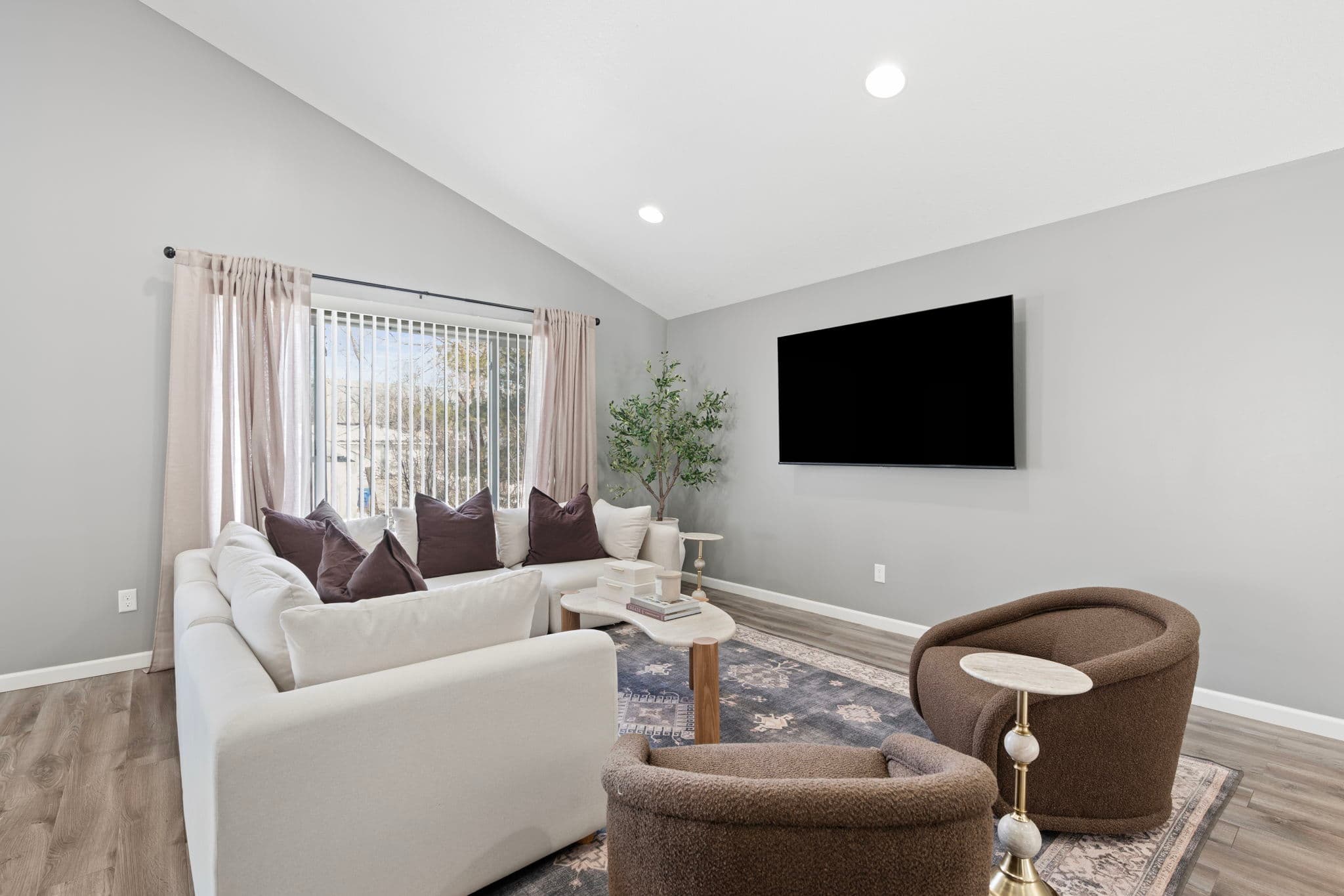 Living room corner with sectional under a large window and olive tree
