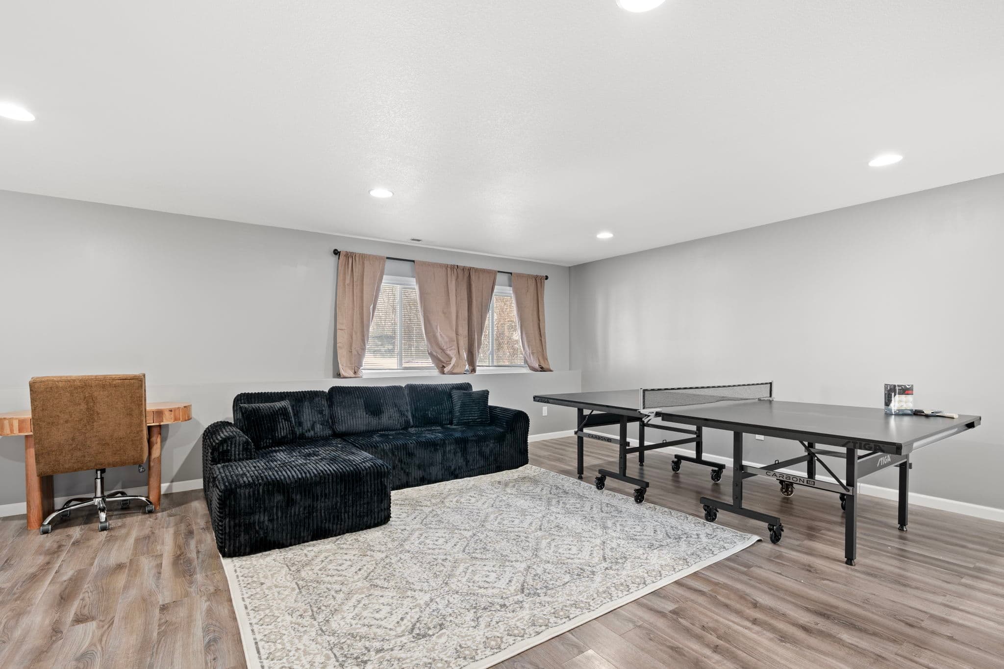 Rec room seating area with sectional, desk, and daylight window