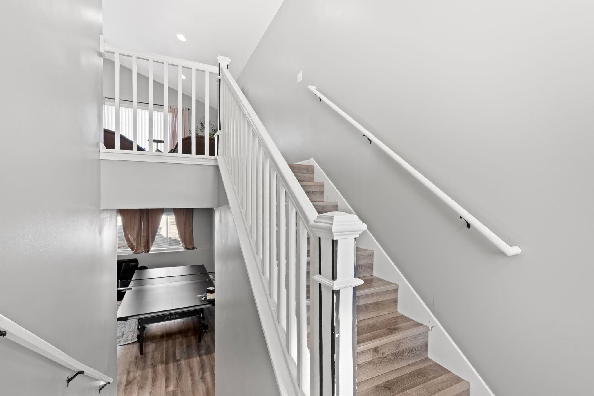 Split-level staircase with white railings, looking up to the living room and down to the rec room